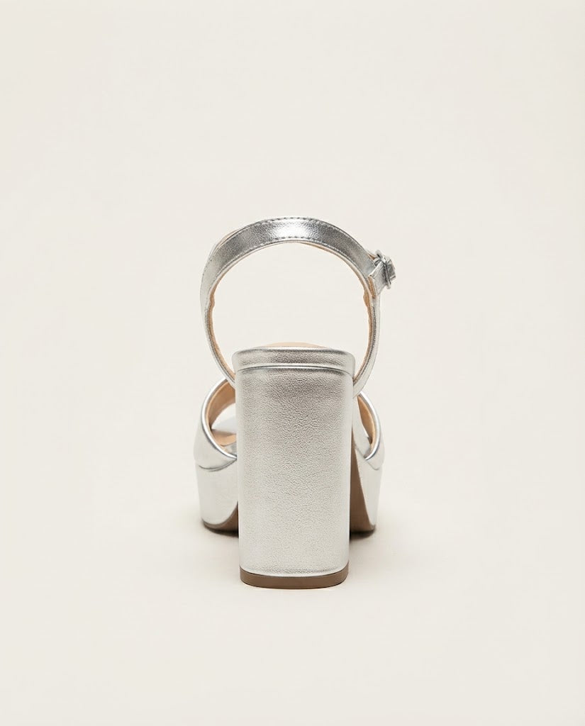 A single metallic silver high-heeled sandal shown from the back against a plain off-white background.