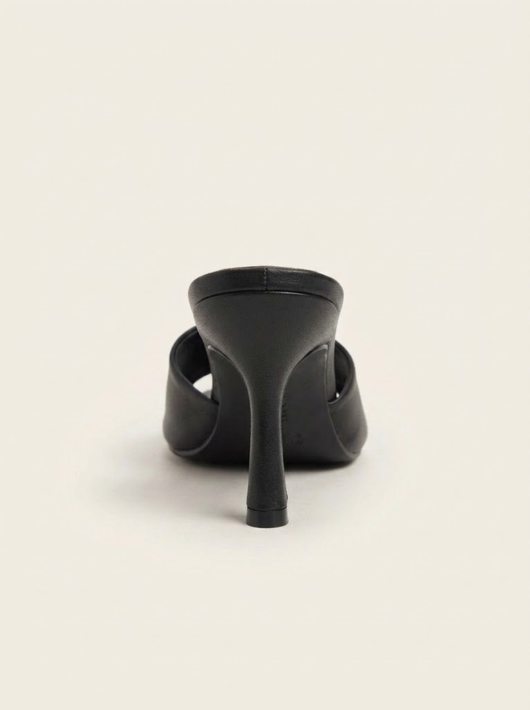 A black leather high-heeled mule sandal shown from a rear three-quarter view against a solid off-white background.