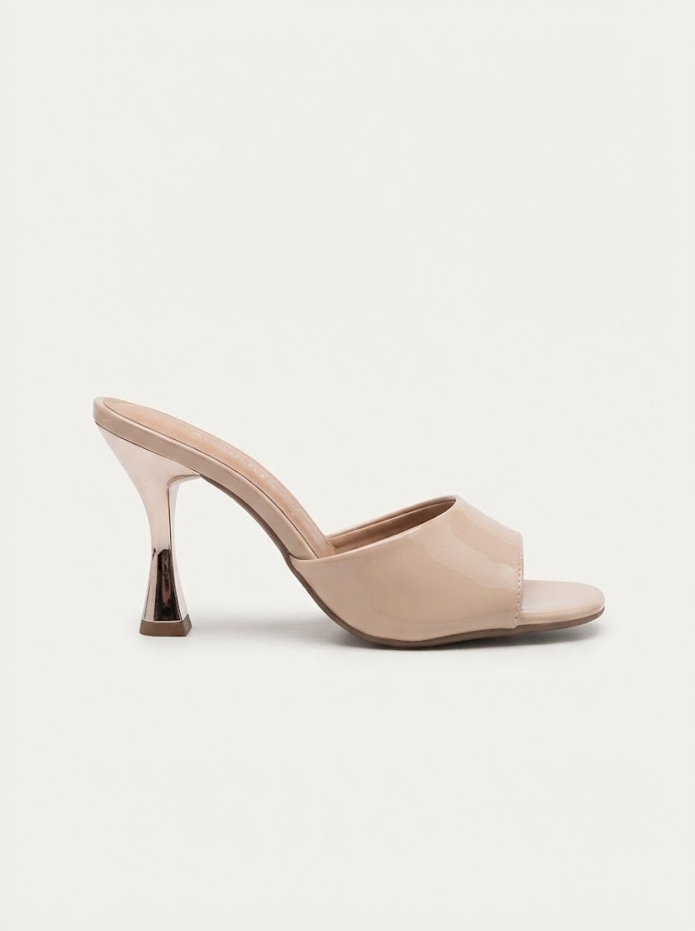 A single nude beige patent leather mule sandal with a low block heel and a metallic gold cone tip, shown from a side profile on a light off-white background.