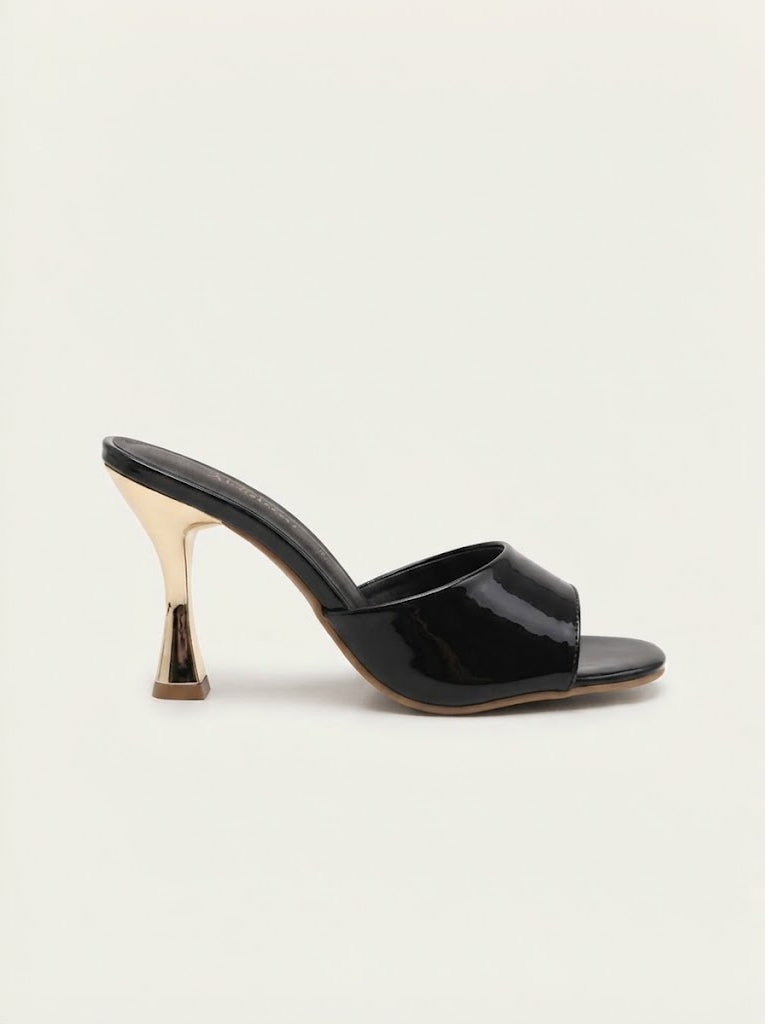 A single black patent leather mule sandal with a sculptural metallic gold high heel, shown from a side profile on a light cream background.