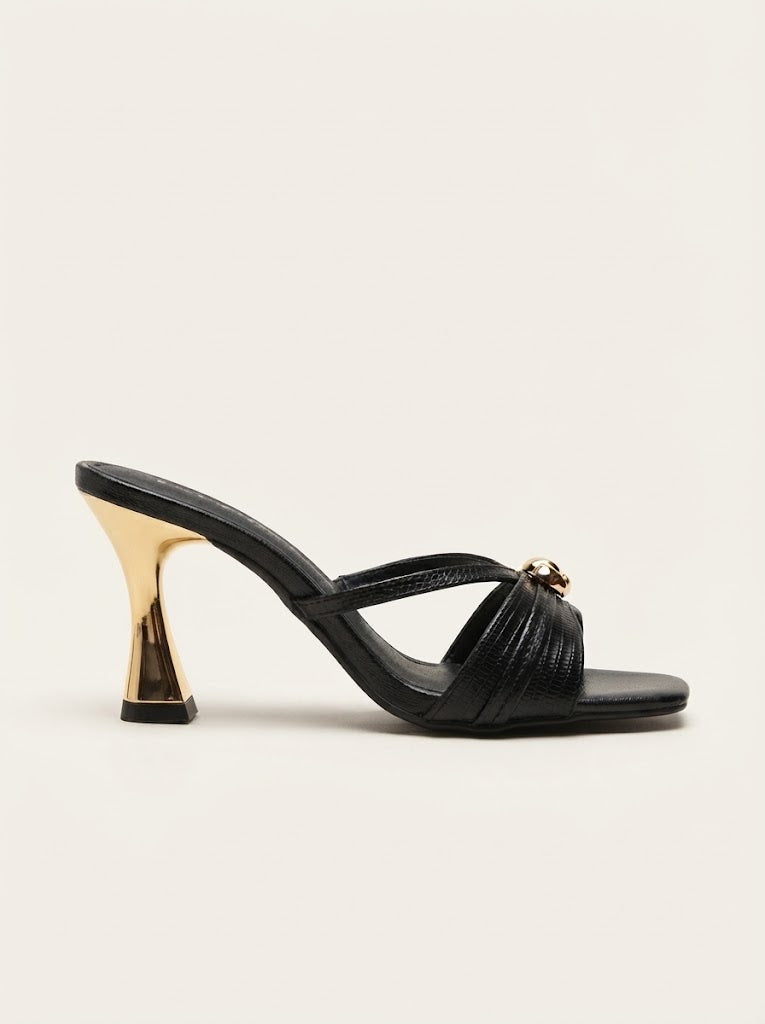 A single black leather mule sandal with a sculptural metallic gold cone heel and a small gold horsebit detail on the front strap, shown against a plain off-white background.