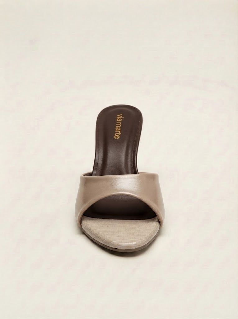 A single women's slide sandal with a wide, open toe strap in a metallic taupe-beige finish, set against a dark brown insole with gold 'Valentino' branding, on a light beige textured background.