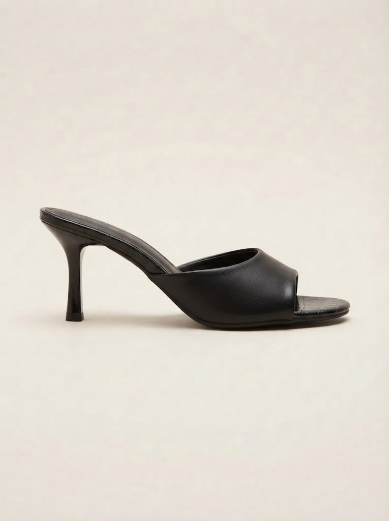 A single black leather mule sandal with a slim high stiletto heel, shown in profile against a light beige background.