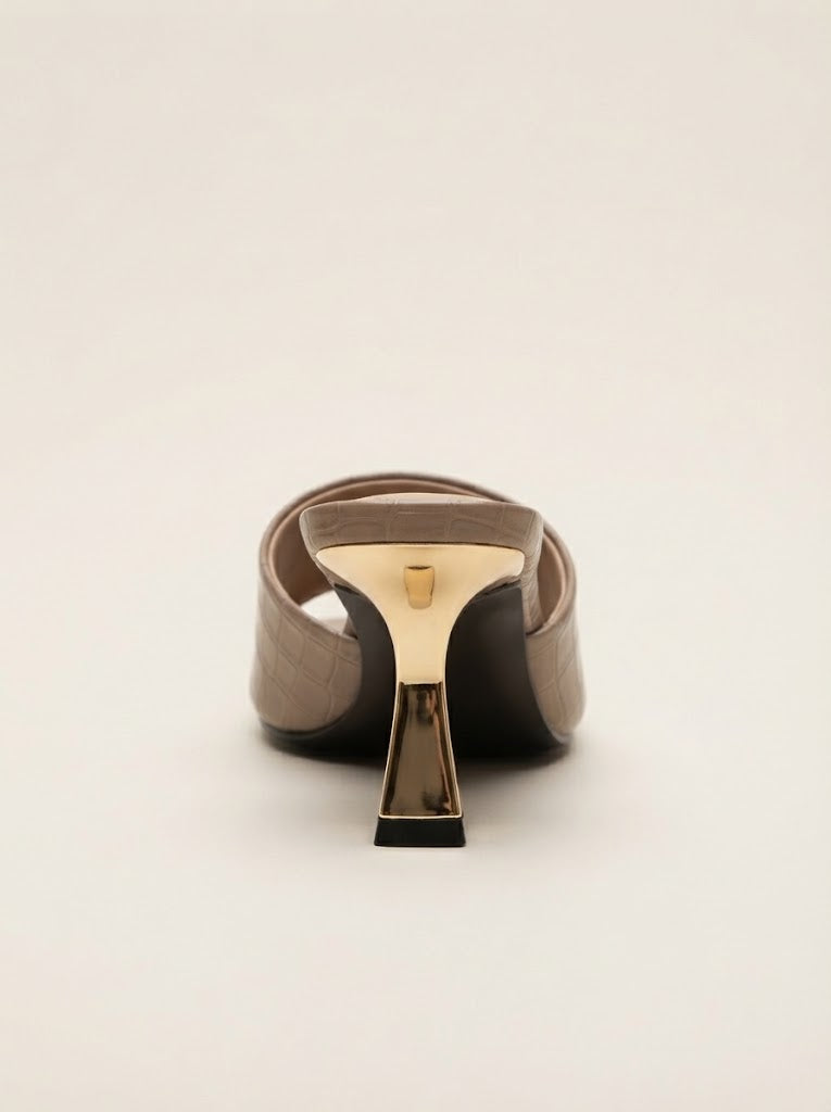 A single taupe-brown slingback mule shoe with a sculptural metallic gold and dark brown geometric heel, shown from a rear three-quarter view on a light beige background.