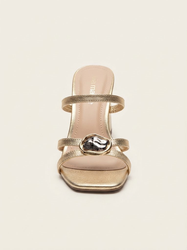 A single metallic gold heeled sandal with two thin straps and a central decorative metallic ring, shown from a top-down view on a light beige background.